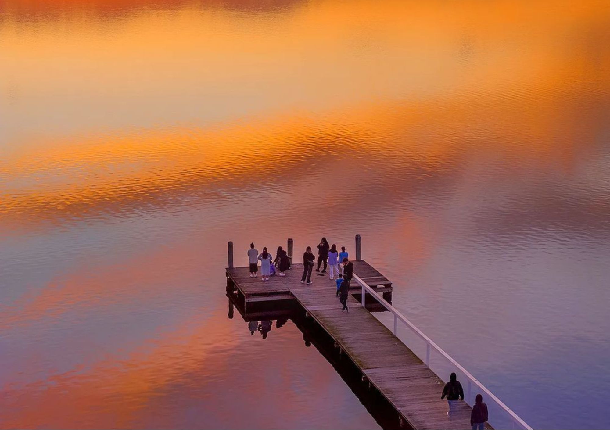 people enjoying a beautiful sunset reflected on the water at long jetty central coast nsw