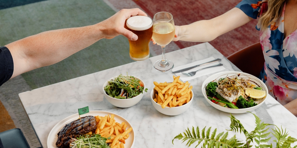 Guests enjoying lunch and drinks at Diggers The Entrance, featuring steak, seafood, salads, and fries served in a relaxed modern dining setting on the Central Coast.