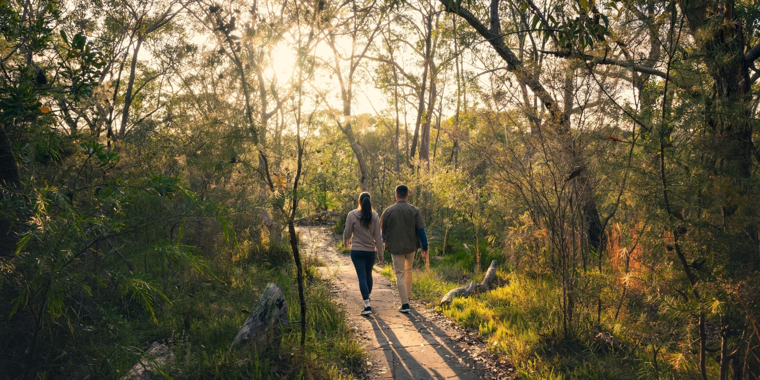 Couple walking through a peaceful bushland trail on the Central Coast near The Entrance.