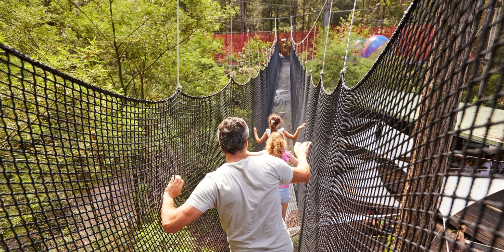 Family crossing a suspended net bridge at Treetops Adventure Park in Ourimbah on the NSW Central Coast.